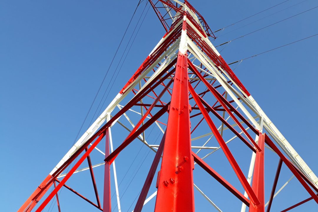 Detail of high voltage towers painted red on top of a mountain.